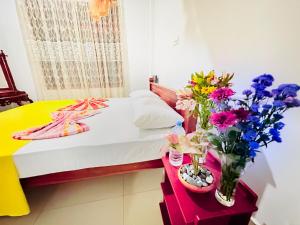 um pequeno quarto com uma cama com flores em vasos em Golden Town Hostel em Tangalle