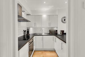 a kitchen with white cabinets and a sink at Contemporary Oasis in Paddington III in London