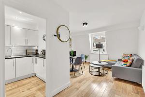 eine Küche und ein Wohnzimmer mit einem Sofa und einem Tisch in der Unterkunft Contemporary Oasis in Paddington III in London