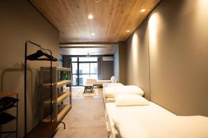 een kamer met 3 bedden en een kamer met een bank bij TasoneUrbanStayOsaka なんば日本橋黒門テナント2F in Osaka