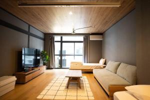een woonkamer met een bank en een tv bij TasoneUrbanStayOsaka なんば日本橋黒門テナント2F in Osaka