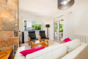 a living room with a white couch and two chairs at Es Claper in Cala Ratjada