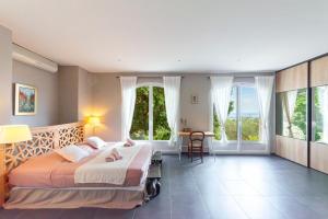 - une chambre avec un grand lit, des fenêtres et une table dans l'établissement Villa Mont des Oiseaux Hyères Piscine Vue Panoramique Mer Grande Terrasse, à Hyères