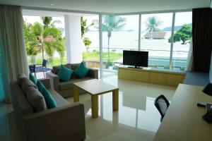 a living room with a couch and a tv and a table at The Beachfront Hotel Phuket in Rawai Beach