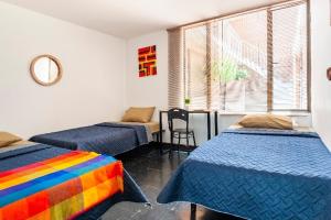 Habitación con 2 camas y manta de arco iris. en Hotel Habitat Hospedaje, en Bogotá