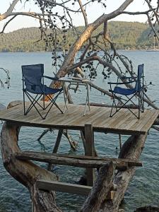 two chairs and a table on a wooden dock on the water at Su camping in Dağpınar
