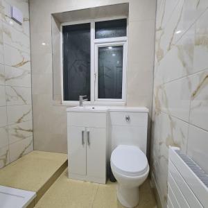 La salle de bains blanche est pourvue de toilettes et d'une fenêtre. dans l'établissement 3 bedroom home - Meadowhall, Magna, Utilita arena, free parking, garden, à Templebrough