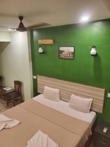 ein Schlafzimmer mit einer grünen Wand und einem Bett in der Unterkunft TP cottages Beach Resort in Arambol