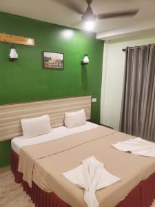 two beds in a room with a green wall at TP cottages Beach Resort in Arambol