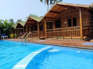 a log cabin with a swimming pool in front of a house at TP cottages Beach Resort in Arambol