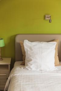 a bed with a white pillow and a green wall at Guesthouse Amfora in Poperinge