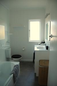 a white bathroom with a toilet and a sink at Nights on Broadway - THE HOUSE in Matamata