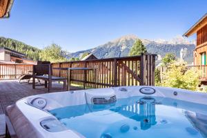 a hot tub on a patio with mountains in the background at Almdorf Hohentauern by ALPS RESORTS in Hohentauern