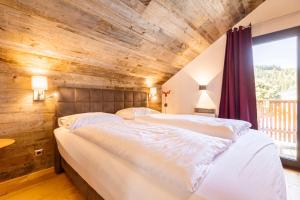 Almdorf Hohentauern by ALPS RESORTS في هوهنتاورن: سريرين في غرفة نوم ذات سقف خشبي