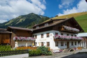 ein großes weißes Gebäude mit Blumen an den Fenstern in der Unterkunft Gästehaus Alpenruh in Holzgau