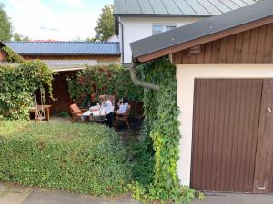 two people sitting at a table outside of a house at Ferienwohnung "Fichtelnaabrauschen" in Fichtelberg