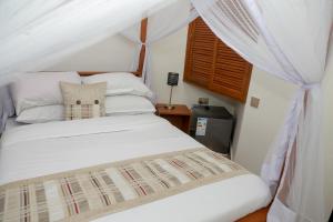 een slaapkamer met een wit bed en een baldakijn bij Wademac Arusha Inn Hotel in Arusha