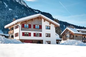 un bâtiment avec de la neige devant une montagne dans l'établissement Haus Margreth, à Mellau