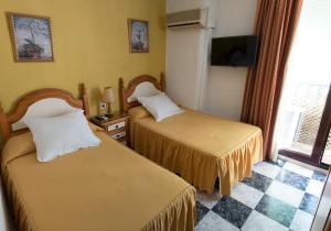 a hotel room with two beds and a tv at Pension Zurita in Granada