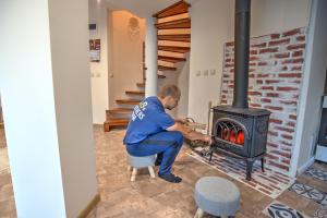 a man is putting something into a stove at Вила Capitalica Forte in Pamporovo