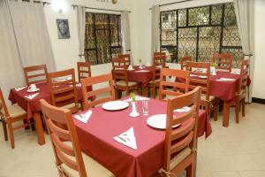restauracja ze stołami i krzesłami z czerwoną tkaniną w obiekcie Wademac Arusha Inn Hotel w mieście Arusza