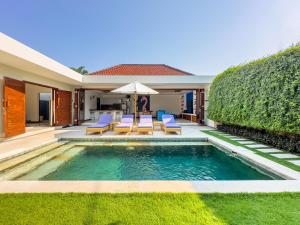 a backyard with a pool and chairs and an umbrella at Villa Bugis Kayu Aya Seminyak in Seminyak