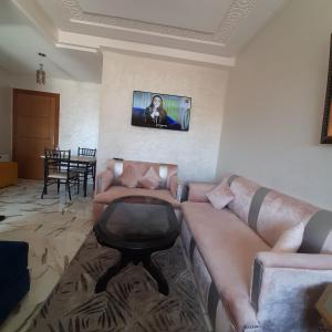 ein Wohnzimmer mit einem Sofa und einem TV an der Wand in der Unterkunft résidence kaoutare in Meknès