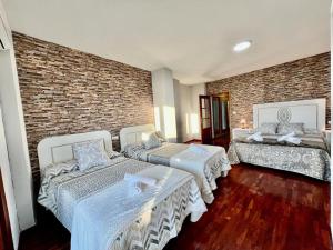 a room with three beds and a brick wall at VIVIENDA REAL CON ENCANTO in Úbeda