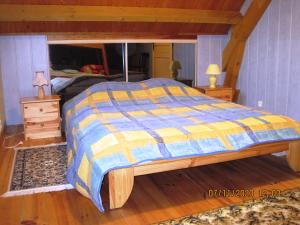 a bed with a blue and yellow comforter in a bedroom at 77 Rue de la Bresse in Nance