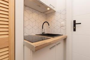 een keuken met een wastafel en een kruis aan de muur bij Studio Metro Wilanowska Warsaw Mokotów by Renters in Warschau