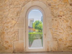 uma janela arqueada numa parede de pedra com vista em Snug holiday home in Bergerac with terrace em Bergerac