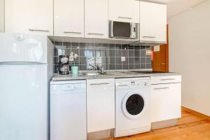 a kitchen with white cabinets and a washer and dryer at Alfama Charming Apartment in Lisbon