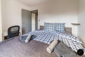 a bed with a blue and white checkered blanket and a chair at Escapade lumineuse, à 5 min de la plage et du port in Toulon