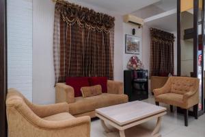 a living room with a couch and two chairs and a table at RedDoorz Plus At Grand Populer Hotel in Makassar