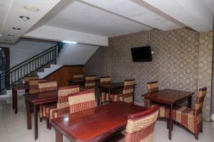 a restaurant with tables and chairs and a television on the wall at RedDoorz Plus At Grand Populer Hotel in Makassar