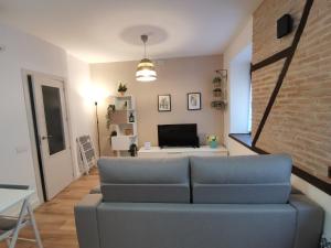 a living room with a blue couch and a brick wall at Casa de los Canteros in Toledo