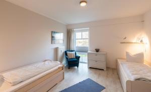 a bedroom with two beds and a chair and a window at Ferienwohnung Zeitlos in Kappeln