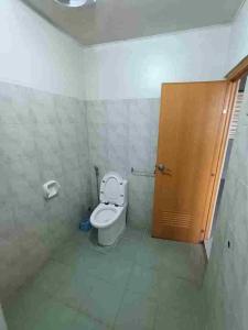 a bathroom with a toilet and a wooden door at Dagat-Dagatan Beach House Bungalow Resthouse Gubat in Gubat