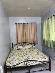 a small bedroom with a bed with a floral bedspread at Dagat-Dagatan Beach House Bungalow Resthouse Gubat in Gubat