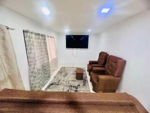 HomeStay Private Home في سوفا: غرفة معيشة مع كرسيين وتلفزيون بشاشة مسطحة