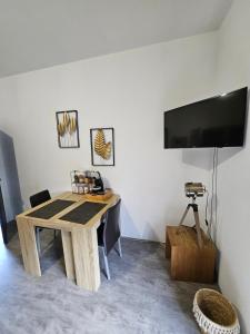 Zimmer mit einem Holztisch und einem Flachbild-TV in der Unterkunft Les ateliers 