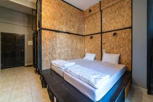 Ce lit se trouve dans un dortoir doté d'un mur en bois. dans l'établissement Joox B - Serviced Apartment, à Betong