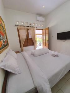 a bedroom with two white beds and a television at Hotel Maerakatja Yogyakarta in Jetis