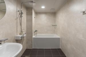 a bathroom with a white tub and a sink at Two H Hotel in Busan