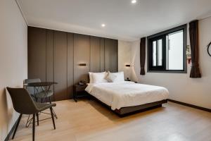 1 dormitorio con 1 cama, 1 mesa y 1 silla en Two H Hotel, en Busan