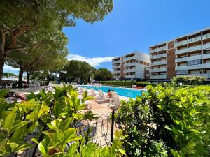 a pool with people sitting on chairs next to a building at Signora Ruth - Aprilia Residence in Aprilia Marittima