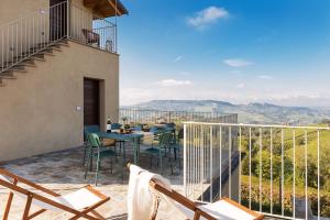 een patio met een tafel en stoelen op een balkon bij I Ciabot di Monforte in Monforte dʼAlba