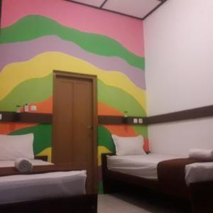 a room with two beds and a colorful wall at Hotel Maerakatja Yogyakarta in Jetis