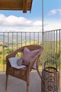 una silla de mimbre con un libro y una taza de café en el balcón en I Ciabot di Monforte, en Monforte dʼAlba