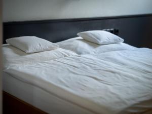 two white beds with white sheets and pillows at Weingut & Gästezimmer Zillinger in Ebenthal